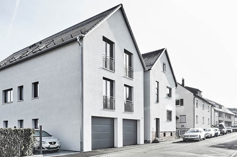 Außenansicht Neubau modernes, weißes Zweifamilienhaus mit Satteldach und grauen Fenstern