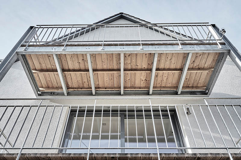 Moderner Balkon aus Stahl und Holz auf weißem Gebäude Einfamilienhaus