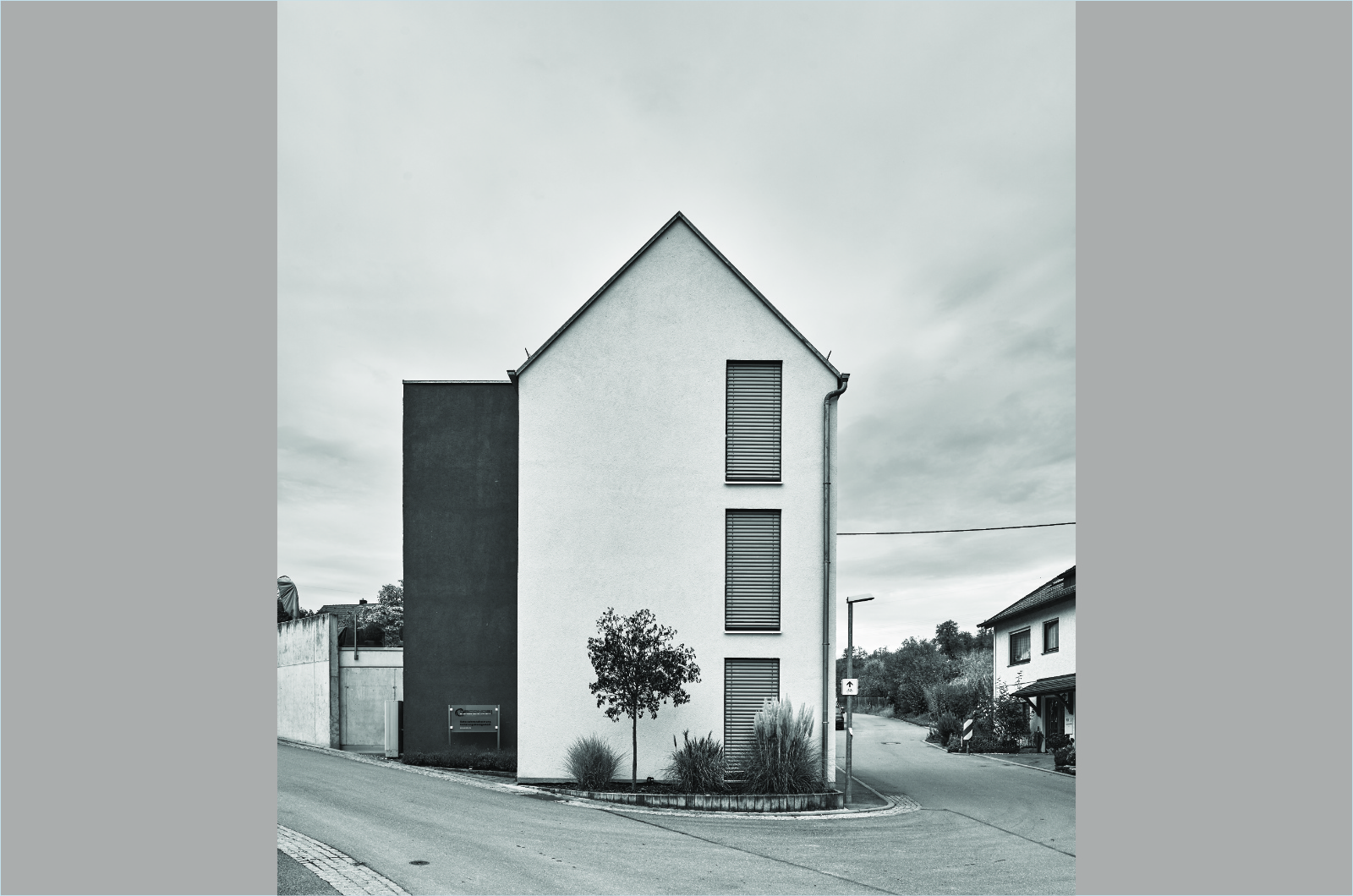 Modernes Gebäude neben Kastanienbaum und altem Fachwerkbau