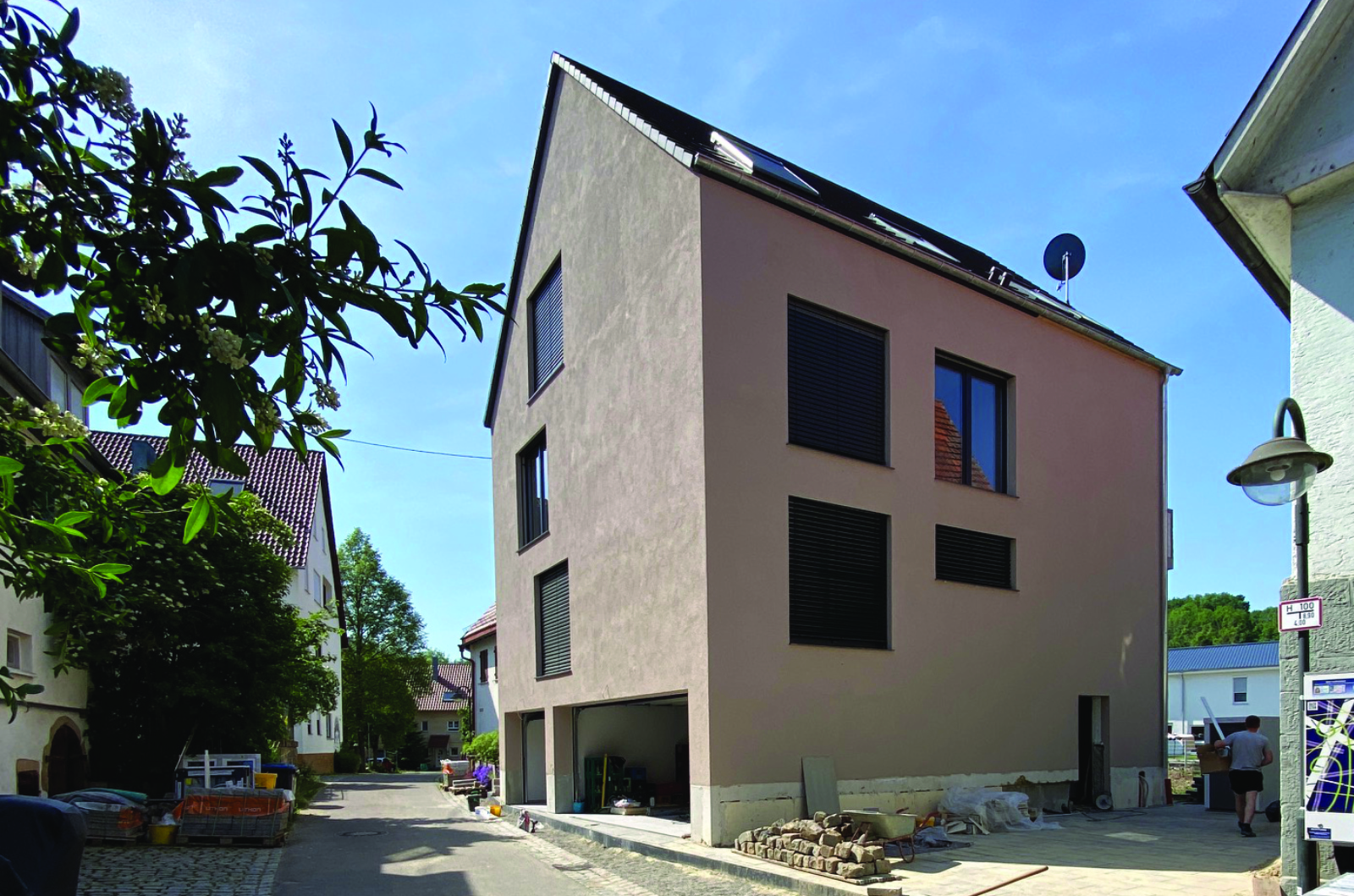 Mehrfamilienhaus mit Sichtbeton im unteren Bereich, darüber weiß verputzt und mit Satteldach und Garage